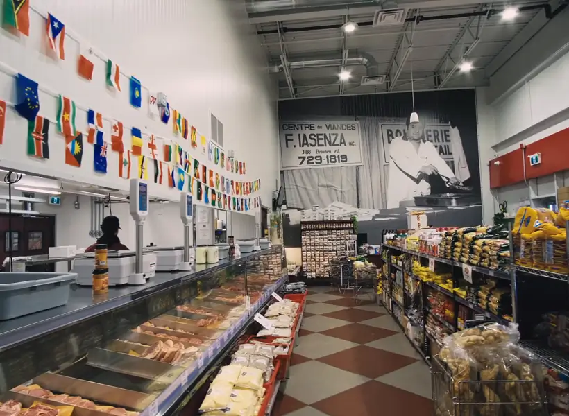 Allée d'épicerie et comptoirs réfrigérés sous les drapeaux du monde dans une succursale Iasenza